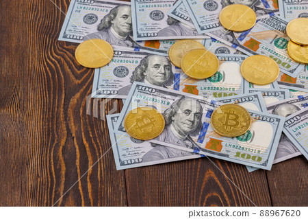 bitcoin coins scattered over US dollar paper banknotes on wooden background bitcoin coins scattered over US dollar paper banknotes on wooden background 88967620