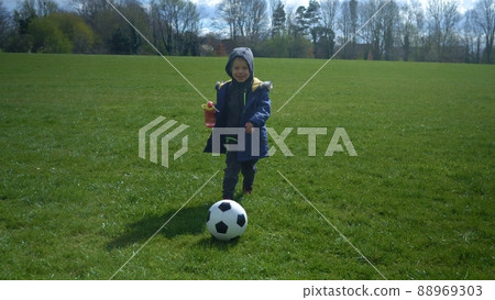 Happy Family Of Children Having Fun In Spring Park. Little Kid Run. Child Boy Dribbles Black White Classic Soccer Ball On Green Grass. People Playing Football. Childhood, Sport, Championship Concept 88969303
