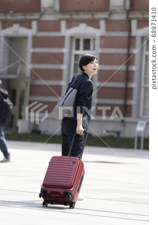 A young woman in a suit walking with a carry bag 88971410
