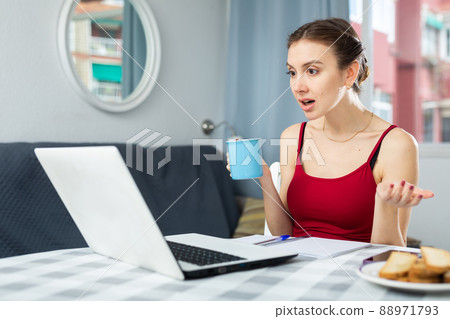 Woman drinking coffee while having video call conversation at home 88971793
