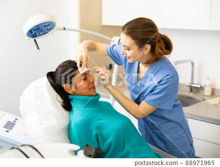Beautician using white pencil and ruler for marking skin of latin woman Beautician using white pencil and ruler for marking skin of latin woman 88971965