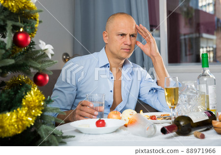 Lonely man drinking alcohol at the christmas table Lonely man drinking alcohol at the christmas table 88971966
