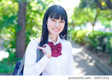 一個高中女生走在美麗城市一條清新的綠色道路上，上學，上下學，未來的課程，在前面的中間，一條充滿綠色的道路 88972582