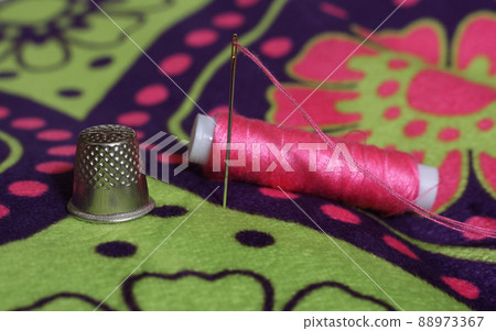 Thimble and Spool of Pink Thread on Vintage Floral Fabric Thimble and Spool of Pink Thread on Vintage Floral Fabric 88973367