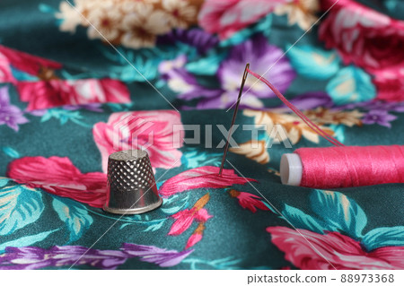 Thimble With Needle and Pink Thread on Vintage Floral Satin Fabric 88973368