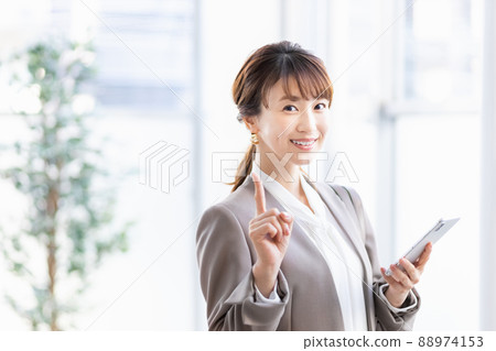 A business woman standing by a bright window with a smartphone 88974153