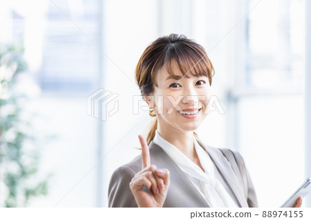 A business woman standing by a bright window with a smartphone 88974155