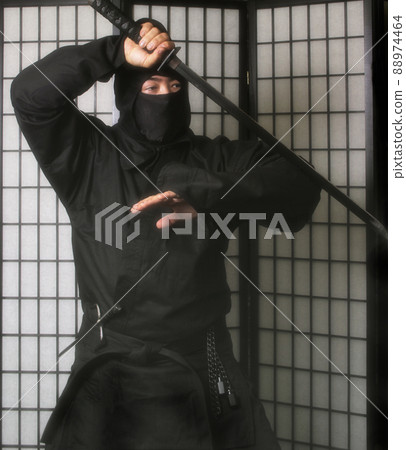 Asian Man Wearing Ninja Costume and holding Ninja Weapons 88974464