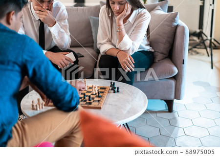 Multiethnic group of business people playing chess while having a break in relaxation area at modern startup office 88975005
