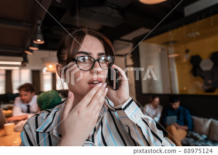 Businesswoman with glasses using mobile phone at modern startup open plan office interior. Selective focus  88975124