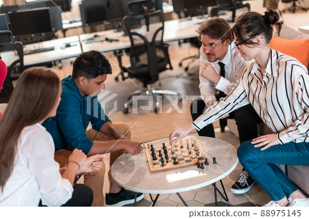 Multiethnic group of business people playing chess while having a break in relaxation area at modern startup office Multiethnic group of business people playing chess while having a break in relaxation area at modern startup office 88975145