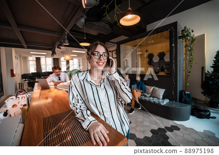 Businesswoman with glasses using mobile phone at modern startup open plan office interior. Selective focus  88975198