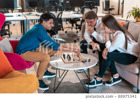 Multiethnic group of business people playing chess while having a break in relaxation area at modern startup office Multiethnic group of business people playing chess while having a break in relaxation area at modern startup office 88975341