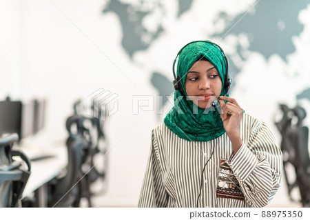 Muslim female with green hijab scarf customer representative business woman with phone headset helping and supporting online with customer in modern call centre Muslim female with green hijab scarf customer representative business woman with phone headset helping and supporting online with customer in modern call centre 88975350
