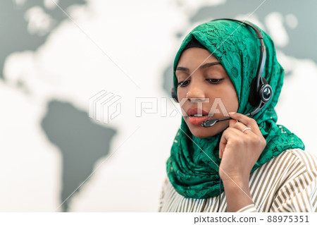 Muslim female with green hijab scarf customer representative business woman with phone headset helping and supporting online with customer in modern call centre Muslim female with green hijab scarf customer representative business woman with phone headset helping and supporting online with customer in modern call centre 88975351