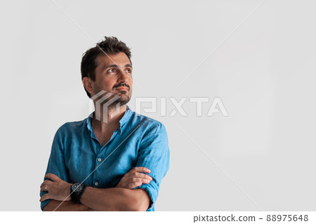 Formal business male portrait. A confident successful casual businessman or manager stands in front of a white background, arms crossed, looking directly at the camera and smiling friendly. High 88975648