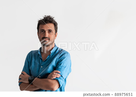 Formal business male portrait. A confident successful casual businessman or manager stands in front of a white background, arms crossed, looking directly at the camera and smiling friendly. High 88975651