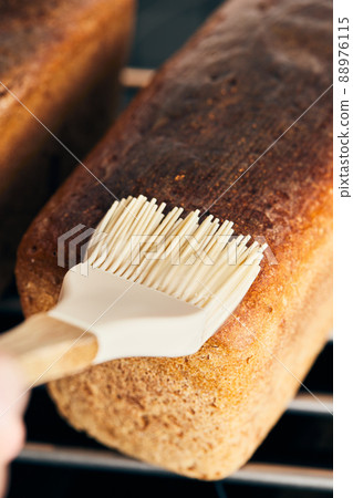 The process of making rye molded bread. Coating the finished bread with starch jelly. Vertical photo. The process of making rye molded bread. Coating the finished bread with starch jelly. Vertical photo. 88976115