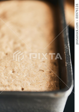 The process of making rye bread. The dough on the rye bread is laid out in a mold. End of dough proofing. Vertical photo. The process of making rye bread. The dough on the rye bread is laid out in a mold. End of dough proofing. Vertical photo. 88976116