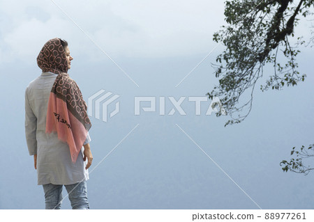 Rear viewpoint of a young Muslim woman enjoying in the misty Rear viewpoint of a young Muslim woman enjoying in the misty 88977261