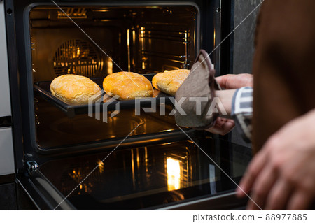 Close-up. The cook prepares bread in an electric oven. 88977885