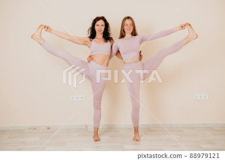 Well looking middle aged sporty woman, fitness instructor in pink sportswear doing stretching and pilates on yoga mat in the studio with mirror. Female fitness yoga. Healthy lifestyle and harmony. 88979121