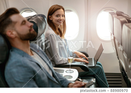 Joyful woman working on notebook in airplane 88980970