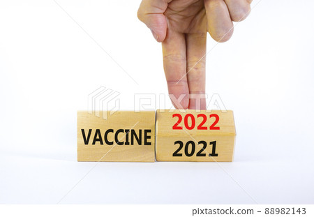 Symbol of covid-19 vaccine in 2022. Doctor turns a wooden cube and changes words 'vaccine 2021' to 'vaccine 2022'. Beautiful white background, copy space. Medical, covid-19 vaccine in 2022 concept. 88982143