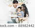 Portrait of young asian parents keep in arms, hugging child kid baby boy,celebrating birthday holiday party on a minimal background with air balloons.Cake for 1 year.Happy family 88982442