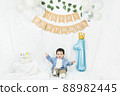 Asian baby boy celebrating first birthday,Cake for 1 year.Infant, small cute child dressed in t-shirt and blue shirt sitting on the floor with a minimal background,white balloons and birthday flag. 88982445