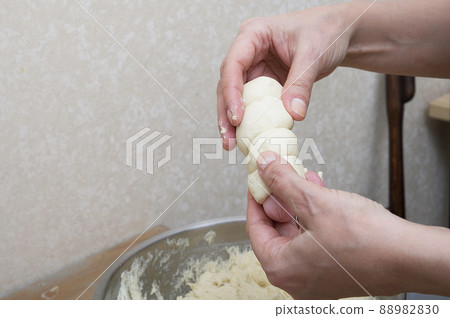 Women's hands carefully hold a sausage wrapping it in dough in the home kitchen. The process of preparing a hot dog close-up. Women's hands carefully hold a sausage wrapping it in dough in the home kitchen. The process of preparing a hot dog close-up. 88982830