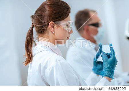 female scientist putting on a protective mask in the lab. female scientist putting on a protective mask in the lab. 88982905