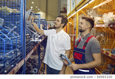 Sales assistant at hardware store helping customer choose new hose for washing machine Sales assistant at hardware store helping customer choose new hose for washing machine 88983100