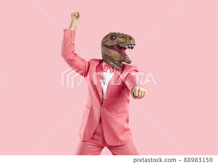Funny crazy man in pink suit and dinosaur mask dancing isolated on pink background 88983150