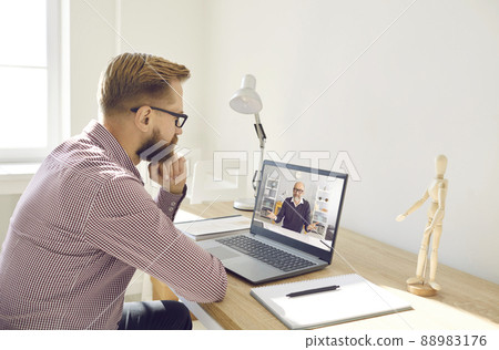 Serious man watching video lecture or having online class with remote teacher on laptop 88983176