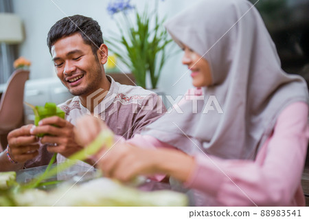muslim couple asian making ketupat rice cake at home using palm leaf 88983541