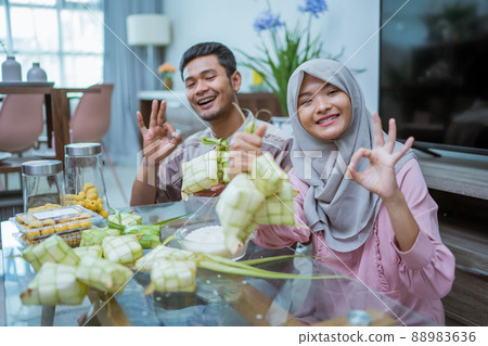 muslim couple asian making ketupat rice cake at home using palm leaf thumb up muslim couple asian making ketupat rice cake at home using palm leaf thumb up 88983636
