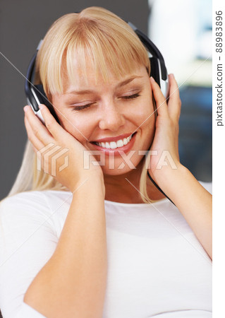 Woman with eyes closed listening to music. Closeup of relaxed young woman listening to headphones. Woman with eyes closed listening to music. Closeup of relaxed young woman listening to headphones. 88983896