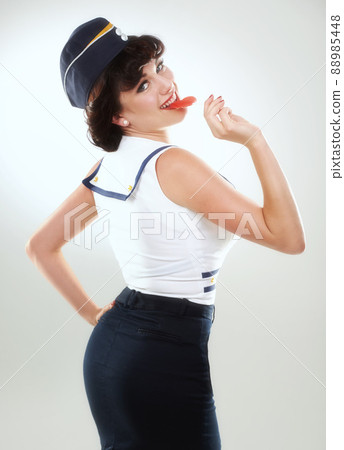 Naughty in naughtical. A sailor pinup girl posing against white with a lollipop. 88985448