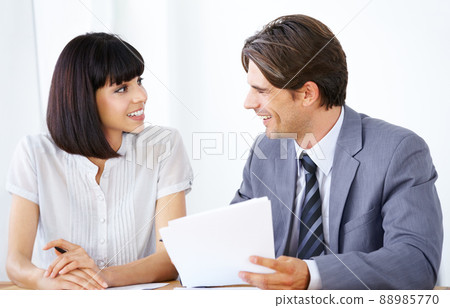 Putting their minds together to succeed. Two young executives enjoying a conversation in the office together. Putting their minds together to succeed. Two young executives enjoying a conversation in the office together. 88985770