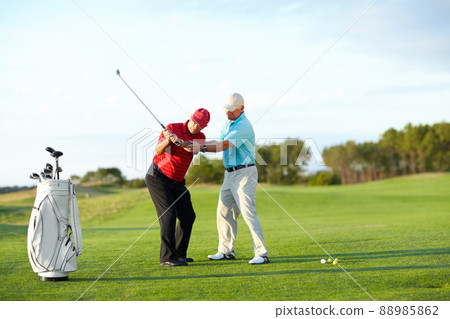 The correct technique. A male golfer getting help from his caddy on the golf course. 88985862