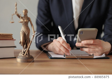 selective focus, female lawyer or judge checks documents or a contract and makes notes in a notebook and phone, is engaged in the registration of divorce proceedingss or contracts via the Internet selective focus, female lawyer or judge checks documents or a contract and makes notes in a notebook and phone, is engaged in the registration of divorce proceedingss or contracts via the Internet 88985875