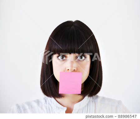 Stress is stifling her creative voice. Conceptual image of a young businesswoman with a pink post-it note covering her mouth. 88986547