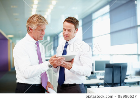 Executives using tablet PC. Handsome business man with colleague using tablet PC in office. Executives using tablet PC. Handsome business man with colleague using tablet PC in office. 88986627
