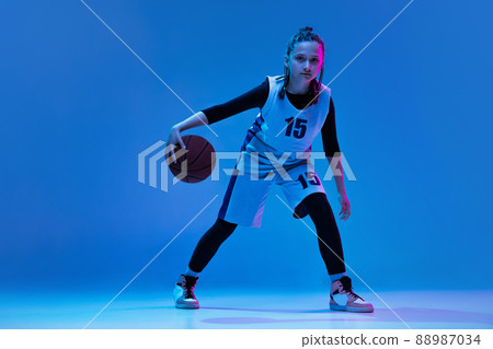 Portrait of teen girl, basketball player in motion, dribbling ball isolated over white studio background. Active game 88987034