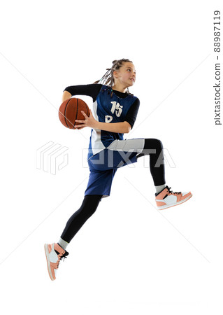 Throwing ball in a jump. Portrait of teen girl in blue uniform training, playing basketball isolated over white background. 88987119