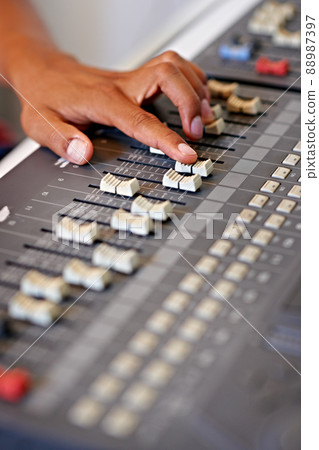 Fine-tuning the mix. Cropped close-up image of a hand moving a slider on a mixing desk. 88987397