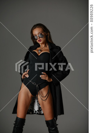 Sexy woman in black swimsuit and black high boots. Fashion young woman with long legs posing at studio. Sexy woman in black swimsuit and black high boots. Fashion young woman with long legs posing at studio. 88989226
