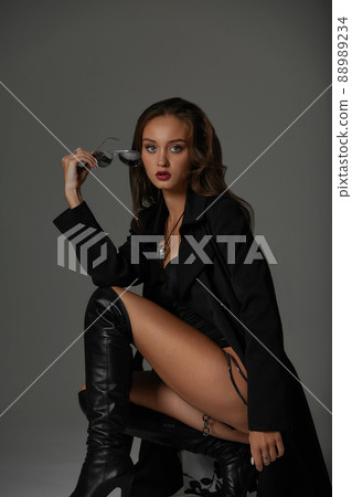 Pretty female with dark hair in a black swimsuit sit on chair. vamp woman Pretty female with dark hair in a black swimsuit sit on chair. vamp woman 88989234