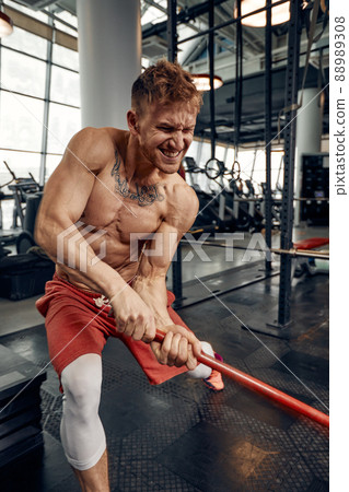 Man fitness training with large and heavy tire hits hammer. Concept workout, cross strength Man fitness training with large and heavy tire hits hammer. Concept workout, cross strength 88989308